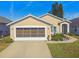 Tan one-story house with white garage door, landscaping, and paved driveway at 152 Travis Ln, Davenport, FL 33837