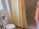 Cozy bathroom with a toilet, shower with a yellow curtain, and a small window at 2595 Edenville Path, The Villages, FL 32162