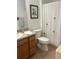 Functional bathroom with wood vanity, toilet, and shower with decorative curtain at 2595 Edenville Path, The Villages, FL 32162