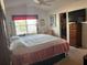 Comfortable bedroom featuring a ceiling fan, large window, and a TV atop a wooden dresser at 2595 Edenville Path, The Villages, FL 32162