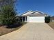 Inviting home with a wide driveway leading to a two-car garage, complemented by neat landscaping at 2595 Edenville Path, The Villages, FL 32162