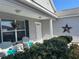 Close up of the inviting front porch, decorated with a floral wreath, seating, and lovely greenery at 2595 Edenville Path, The Villages, FL 32162