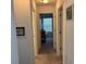 Neutral-colored hallway with carpet leading to bedrooms and decorated with framed pictures at 2595 Edenville Path, The Villages, FL 32162