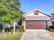 Two-car garage with a brown door and stone accents, complementing the home's exterior at 22004 Belgian Ct, Mount Dora, FL 32757