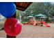 A colorful playground with slides and climbing structures, seen through a foreground of red and blue balloons on a sunny day at 22004 Belgian Ct, Mount Dora, FL 32757