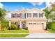 Two-story house with beige walls, red shutters, and a brick driveway at 7405 Sw 108Th St, Ocala, FL 34476