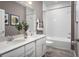 Bathroom with double sink vanity, white cabinets, gray walls, a large mirror, and a shower-tub combination at 1632 Covey Rise Ter, Winter Haven, FL 33884