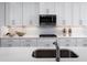 Kitchen detail showcasing white cabinets, stainless steel appliances, quartz countertops, and herringbone backsplash at 1632 Covey Rise Ter, Winter Haven, FL 33884