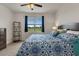 Bright bedroom with a bed featuring decorative patterned bedding, a view of the yard and an accent shelf at 9773 Sw 63Rd Loop, Ocala, FL 34481