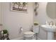 Stylish powder room featuring a pedestal sink, modern fixtures, and decorative wall art at 9773 Sw 63Rd Loop, Ocala, FL 34481