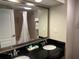Spacious bathroom boasts double sinks with black countertop, large mirror, and accessible shower at 3000 Maingate Ln # 420, Kissimmee, FL 34747