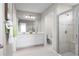 Bright bathroom features a double sink vanity, framed mirror, tiled shower with seat, and tile floors at 1262 Whispering Ln, Minneola, FL 34715