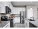 Well-equipped kitchen featuring stainless steel appliances, granite countertops and white cabinets at 1314 Whispering Ln, Minneola, FL 34715