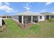 Back of home featuring a screened-in patio area, landscaping and a green lawn at 8750 Sw 79Th Loop, Ocala, FL 34481