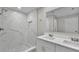 Bathroom with dual vanity, large mirror and shower with marble-style tile and herringbone floor at 20995 Sw 93Rd Lane Rd, Dunnellon, FL 34431