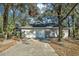 Home featuring a large driveway and an attached garage in a wooded setting at 20995 Sw 93Rd Lane Rd, Dunnellon, FL 34431