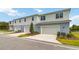 A modern townhome featuring a two-car garage, clean lines, and manicured landscaping, offering curb appeal at 6917 Five Oaks Dr, St Cloud, FL 34773