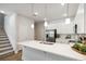 Bright kitchen featuring stainless steel appliances, white cabinets, a large island, and a staircase at 6917 Five Oaks Dr, St Cloud, FL 34773