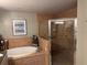 Relaxing bathroom featuring a soaking tub, a separate glass-enclosed shower, and neutral tile at 1425 Ocean Shore Blvd # 402, Ormond Beach, FL 32176