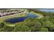 Community aerial view featuring a scenic pond, walking paths, lush trees, and charming houses at 3317 Grande Heron Dr, St Cloud, FL 34773