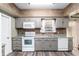 Functional kitchen featuring grey cabinets, white appliances, and a tile backsplash adding a touch of elegance at 3200 Se 34Th St, Ocala, FL 34471