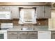 Close up of the kitchen sink with gray cabinetry, backsplash, and appliances at 3200 Se 34Th St, Ocala, FL 34471