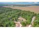 Stunning aerial view of a home surrounded by abundant green trees and a wide-open field beyond at 4931 Tropicana Dr, Indian Lake Estates, FL 33855