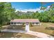 Aerial view of a single-story home surrounded by lush greenery and a long, winding driveway at 4931 Tropicana Dr, Indian Lake Estates, FL 33855