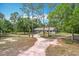 A single-story home with mature trees and a circular driveway, offering privacy and charm at 4931 Tropicana Dr, Indian Lake Estates, FL 33855