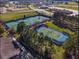 Aerial view of tennis courts in a well-maintained community, surrounded by trees and green space at 8534 Sw 59Th Lane Rd, Ocala, FL 34481