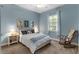 Cozy bedroom with blue walls, a bed with blue accents, wooden rocking chair, and natural light from a window at 248 Lake Tennessee Dr, Auburndale, FL 33823