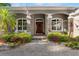 Elegant home entrance with a red door, stone accents, lush landscaping, and a paved walkway at 248 Lake Tennessee Dr, Auburndale, FL 33823