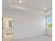 View of the bedroom shows a tray ceiling, neutral walls, window, and bathroom entrance at 9432 Emerald Berry Dr, Winter Garden, FL 34787