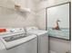 Bright laundry room featuring modern washer and dryer units, storage shelf, and beach-themed wall art at 5228 Luisa Ct, St Cloud, FL 34771