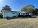 Rear view of light-green single story home with enclosed patio, manicured landscaping, and a well-maintained lawn at 10867 Sw 83Rd Ct, Ocala, FL 34481