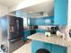 Modern kitchen with stainless steel appliances, granite countertops, mosaic backsplash, and vibrant blue cabinets at 10867 Sw 83Rd Ct, Ocala, FL 34481