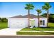 Charming single-story home showcasing a two-car garage, lovely landscaping, and a bright yellow-green front door at 1573 Texas Ave, Sumterville, FL 33585