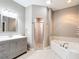 Bathroom with a gray vanity, a glass-enclosed shower, and a large soaking tub at 4649 Sw 103Rd Street Rd, Ocala, FL 34476