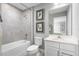 Bathroom boasts a tub with gray tile surround, a white toilet, and vanity with framed botanical art at 11054 Nellie Crossing Cir, Clermont, FL 34711
