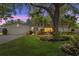 Charming single-story home with lush landscaping, a well-manicured lawn and mature trees at dusk at 1711 Tierra Alta Dr, Lakeland, FL 33813