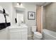 Well-lit bathroom with a tiled shower-tub, white cabinets, modern fixtures, and black and white decorative art at 3034 Cayey Way, Clermont, FL 34711