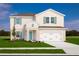 Charming two-story home featuring a two-car garage, manicured lawn, and stylish turquoise front door at 415 Harvard Ct, Dundee, FL 33838
