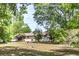 View of the rear exterior showcasing a modest home surrounded by lush trees and a large yard at 910 Nw 56Th Ave, Ocala, FL 34482