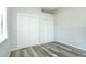 This bedroom features neutral paint, wood-look floors, a window with blinds, and closet with sliding doors at 910 Nw 56Th Ave, Ocala, FL 34482