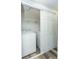 This practical laundry area features a washer, dryer, storage shelf, and sliding closet doors at 910 Nw 56Th Ave, Ocala, FL 34482