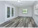 Bright living area boasting gray wood-look flooring, double doors, and natural light through large windows at 910 Nw 56Th Ave, Ocala, FL 34482