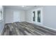 Cozy living room features modern gray wood-look flooring, a white door, and double doors with natural light at 910 Nw 56Th Ave, Ocala, FL 34482