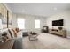 Cozy living room with plush sofa, modern coffee table, large windows, and a flat-screen TV at 9836 Pine Mill Ct, Clermont, FL 34711