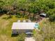An aerial view showcasing this property with a metal roof, a pool, a pond, and mature trees at 13700 Sw 108Th Ln, Dunnellon, FL 34432
