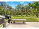 An outdoor grilling station, concrete bench and backyard view are perfect for outdoor relaxation at 13700 Sw 108Th Ln, Dunnellon, FL 34432
